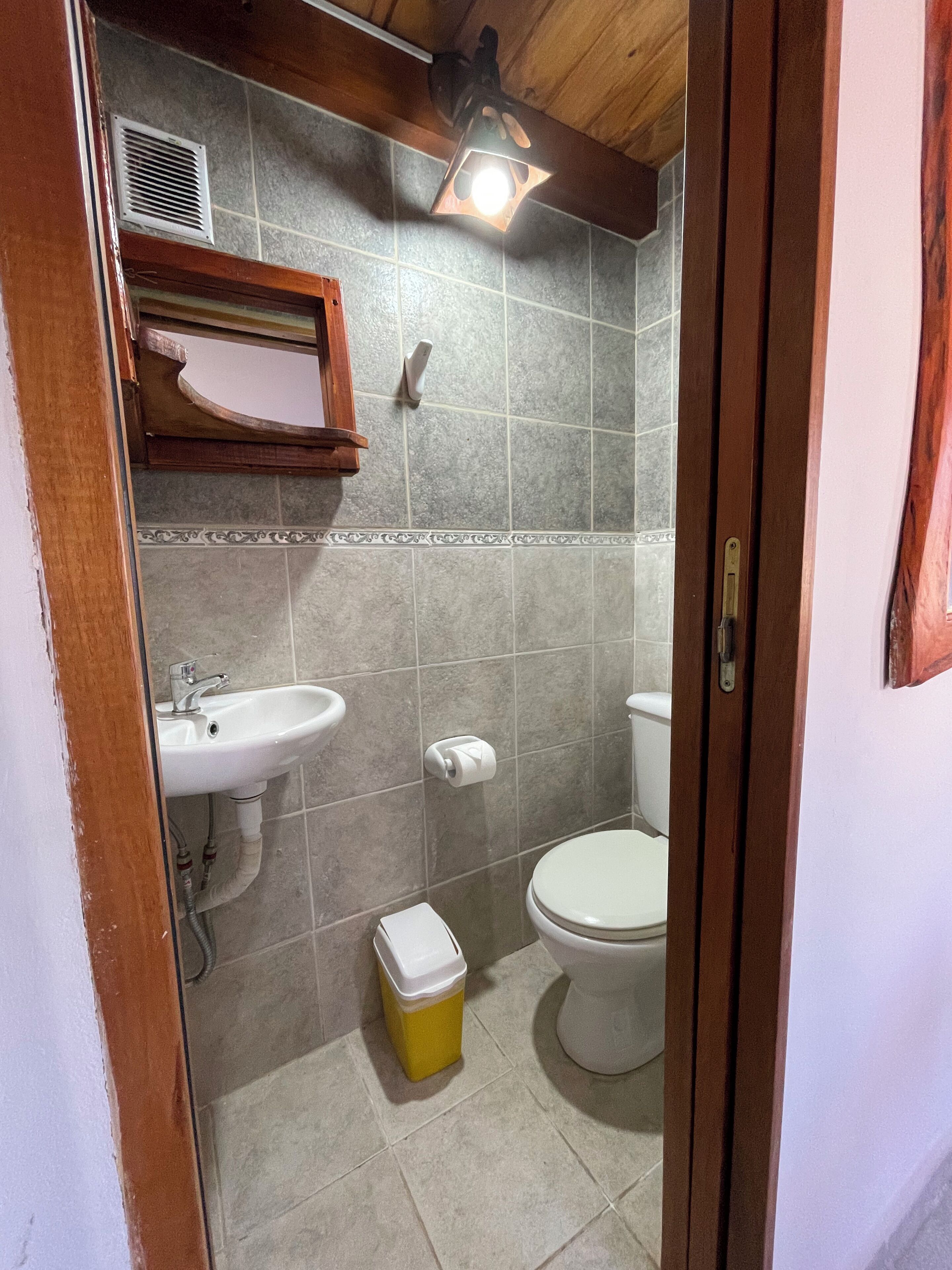 Un baño con lavamanos, inodoro y un cubo de basura.