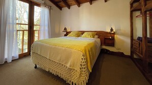 A bedroom with a bed, wooden ceiling beams, a window with curtains, and a bedside table with a lamp. - Paihuen Luxury Suites (Los Reartes)