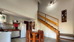 A kitchen with a dining table, chairs, a wooden staircase, a microwave, and a refrigerator. - Paihuen Luxury Suites (Los Reartes)