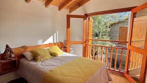 A bedroom with a bed, wooden ceiling beams, a window, and a balcony. - Paihuen Luxury Suites (Los Reartes)