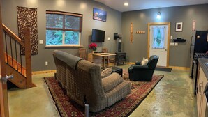 A living room with a fireplace, a TV, and a dining area. - The Little Tiny Cabin "LTC" (Deming)