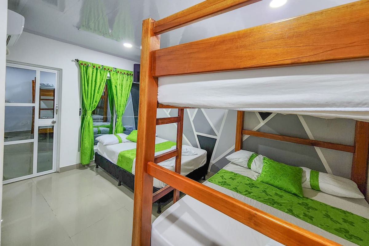 A room with bunk beds, a sliding glass door, and a view of the sea.