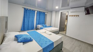 A hotel room with two beds, a bathroom with a shower, and a TV on the wall. - MIRADORES DEL PARAISO  (Puerto Triunfo)