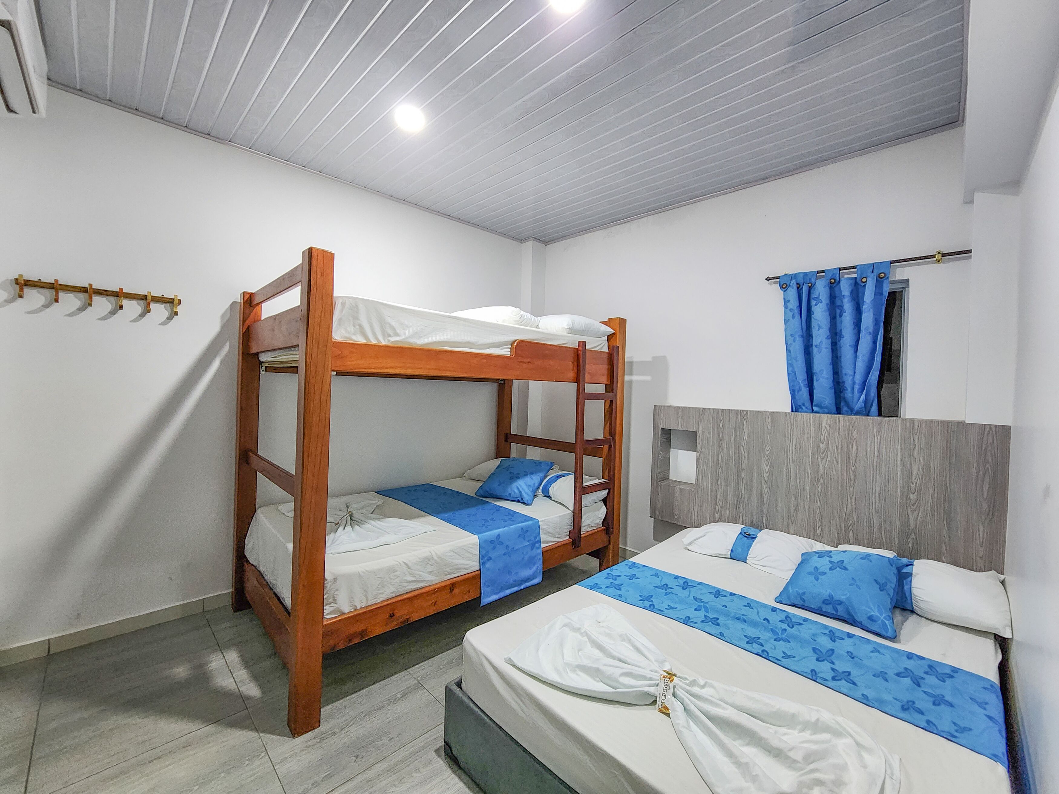Habitación con literas, cabecera de madera, una cama individual y una mesita de noche pequeña.