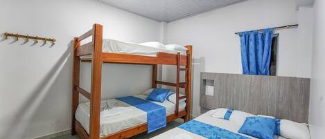 Habitación con literas, cabecera de madera, una cama individual y una mesita de noche pequeña.