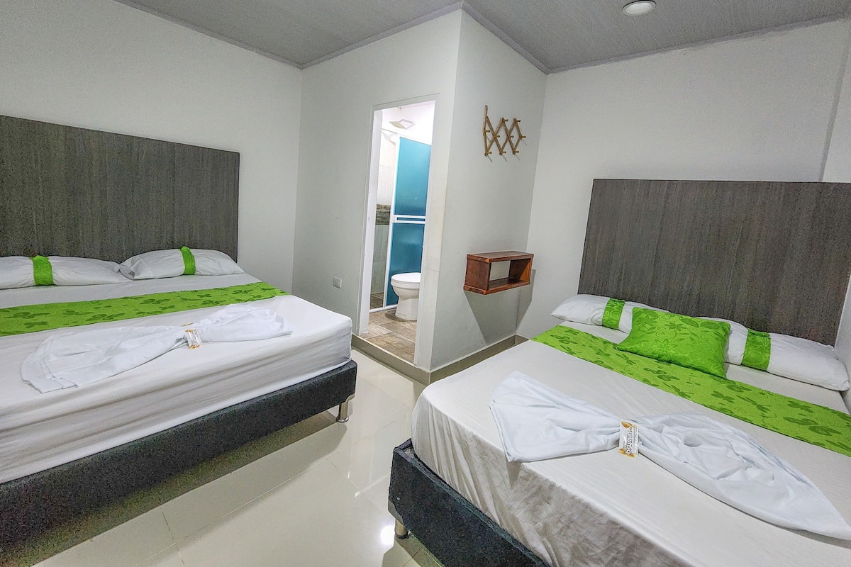 A hotel room with two beds, a bathroom, and a small wooden shelf.
