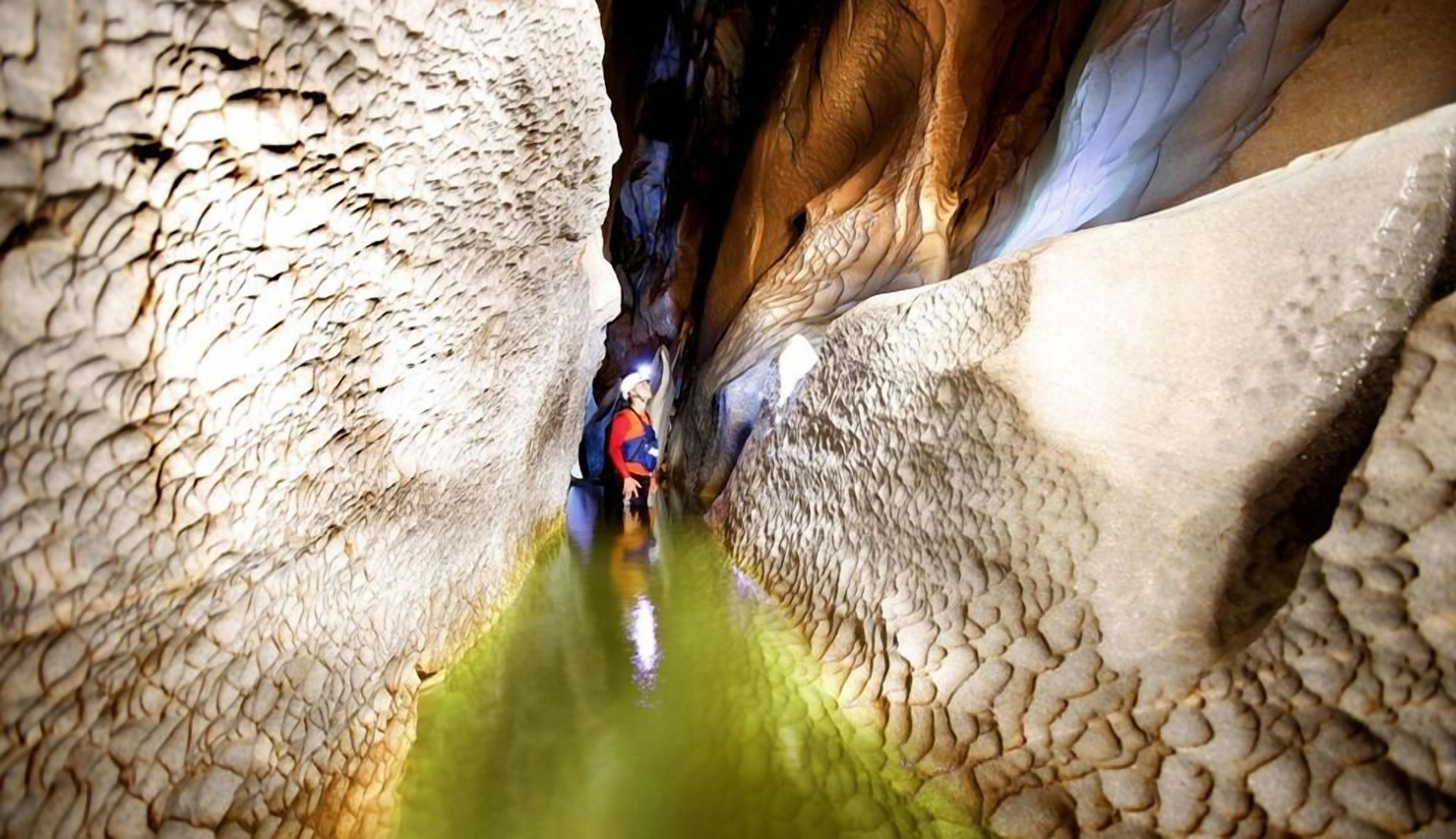 A narrow, rocky canyon with a person standing in the middle.