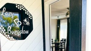 Un pasillo con un letrero que dice "Lazy Bungalow" y vista hacia un comedor con una mesa y sillas.