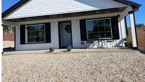A single-story building with a gabled roof, large windows, and a gravel driveway.