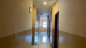 A long, narrow hallway with cream-colored walls and a tiled floor. - Capital O 93285 Residence Hotel Syariah (Medan)