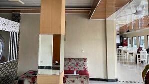 A modern interior with a central column, patterned wall, and a seating area with floral upholstery. - Capital O 93285 Residence Hotel Syariah (Medan)