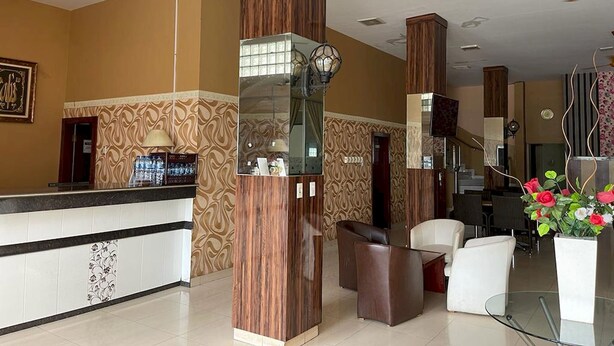 A hotel lobby with a reception desk, seating area, and decorative columns. - Capital O 93285 Residence Hotel Syariah (Medan)