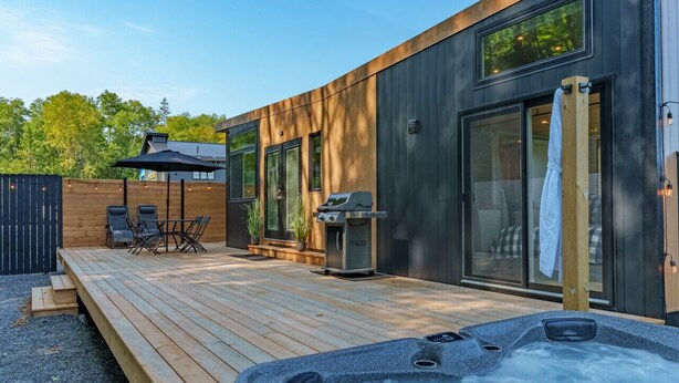 Une terrasse extérieure moderne dotée d’un jacuzzi, d’un espace salon et d’un barbecue.