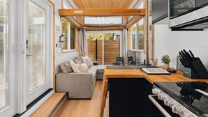 Une cuisine moderne dotée d’une cuisinière intégrée, un coin repas avec une table en bois et un espace détente avec un canapé.