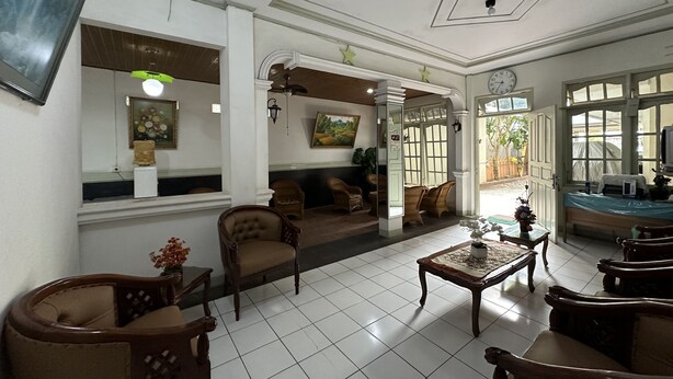 A spacious living room with a sofa, chairs, a coffee table, and a television. - Capital O 93291 Bintang Hotel (Padang)