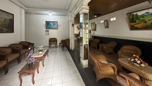 A room with a tiled floor, wooden furniture, and a painting on the wall. - Capital O 93291 Bintang Hotel (Padang)