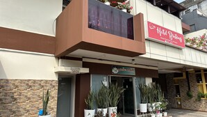 A hotel with a signboard, a balcony with potted plants, and a brick facade. - Capital O 93291 Bintang Hotel (Padang)