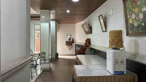 A hotel corridor with a tiled floor, a reception desk, a water dispenser, and a painting on the wall. - Capital O 93291 Bintang Hotel (Padang)