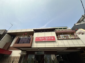 Ein Hotel namens 'Hotel Bintang' mit einer Schautafel, einem Balkon mit Topfpflanzen und blauem Himmel.