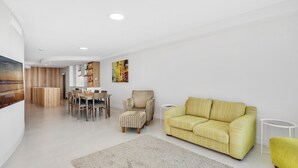 A modern living room with a yellow-striped sofa, a striped armchair, and a dining area with a wooden table and chairs.