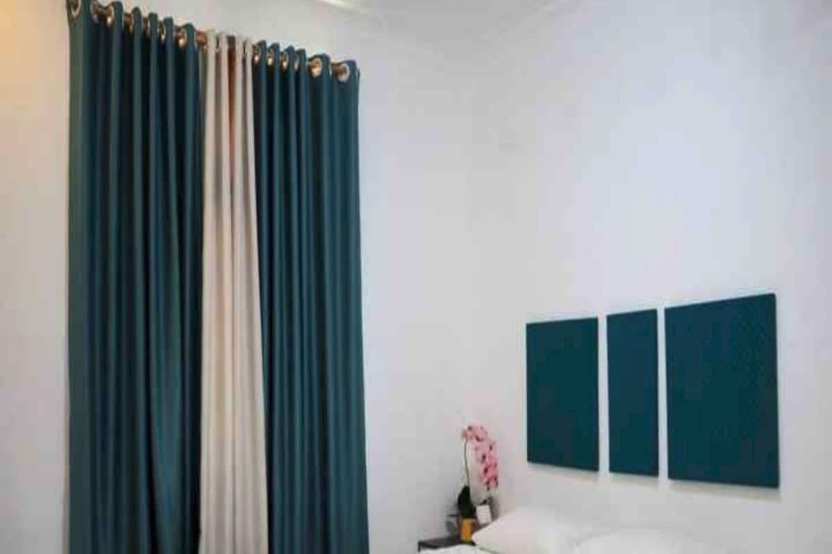 A bedroom with a bed, a nightstand, a lamp, and a window with curtains.