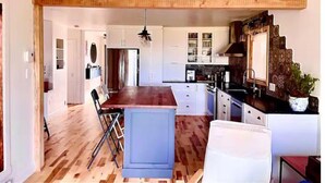 Un'ampia cucina con pavimento in legno, mobili bianchi e un'isola centrale.