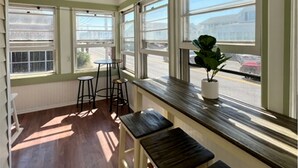 A sunlit room with large windows, wooden benches, and a potted plant. - 5 Bedroom House Steps to the Beach (Old Orchard Beach)