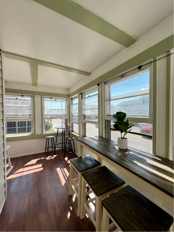 A sunlit room with large windows, wooden benches, and a potted plant.