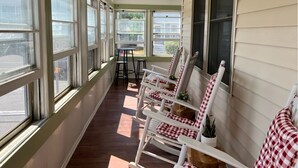 A covered porch with white rocking chairs, a small table, and potted plants. - 5 Bedroom House Steps to the Beach (Old Orchard Beach)