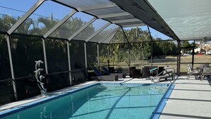 A covered swimming pool with lounge chairs and a dolphin sculpture.