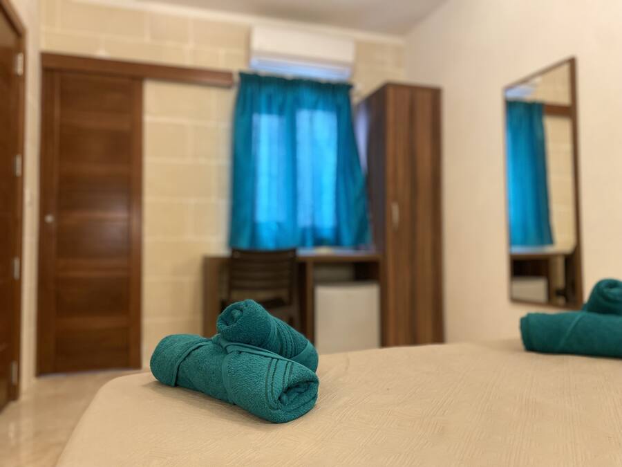 Ein Hotelzimmer mit einem Bett, einem Holzschrank, einem Spiegel und einem Fenster mit blauen Vorhängen.
