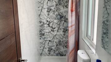 Une salle de bain avec un sol en marbre, des toilettes, un lavabo et un espace douche séparé par un rideau.