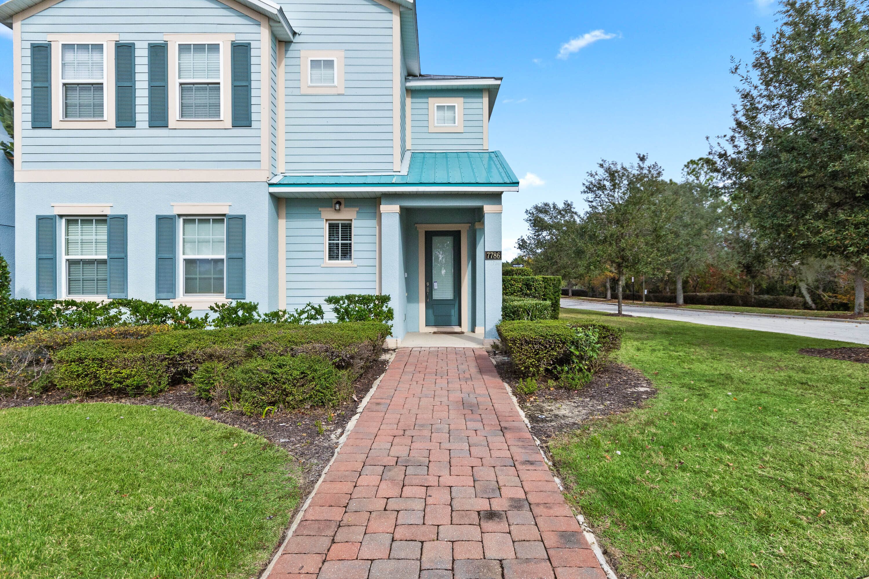 A two-story house with a brick pathway leading to the front door.
