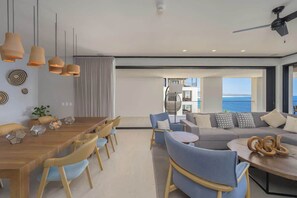 Ein modernes Hotelzimmer mit Essbereich, einer Sofagruppe und einem Balkon mit Blick.