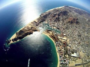 Vista aérea de uma cidade costeira com uma área de praia extensa, intenso desenvolvimento urbano e uma grande massa de água.