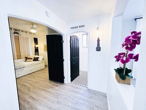 A hallway leading to a powder room with a bed and a window in the adjacent room. - Desert Blooms: Heated Pool & Spa - Winter Oasis (Tucson)