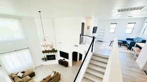 Amplia sala de estar con una escalera, una chimenea y un sofá azul.