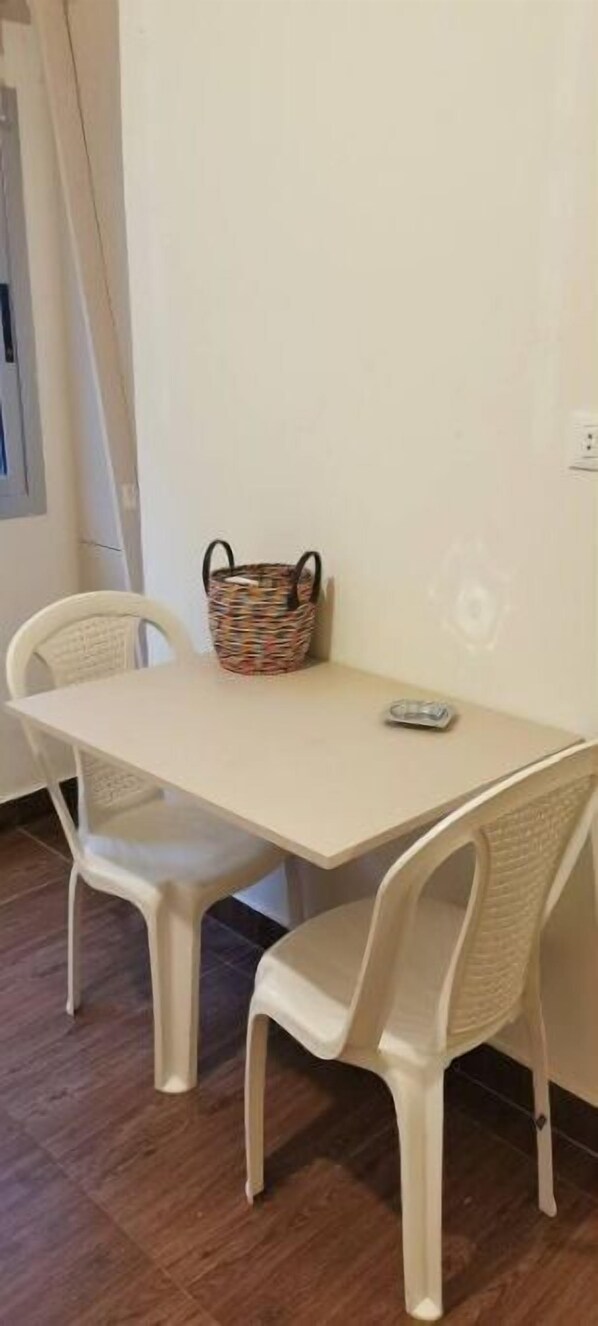 Simple room with a table and two chairs, featuring a woven basket and a small round object.