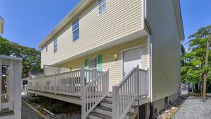 A two-story house with a front porch and a wooden staircase leading to the entrance.
