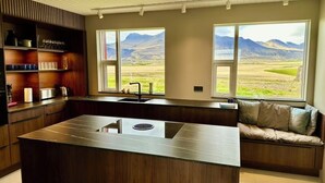 Una cocina moderna con una isla central, estantes empotrados y vistas a montañas a través de grandes ventanales.
