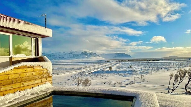 Un edificio moderno con piscina, rodeado de un paisaje nevado y montañas.