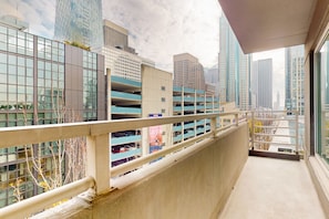 Un balcón con vistas a un paisaje urbano moderno, que incluye rascacielos y un estacionamiento.