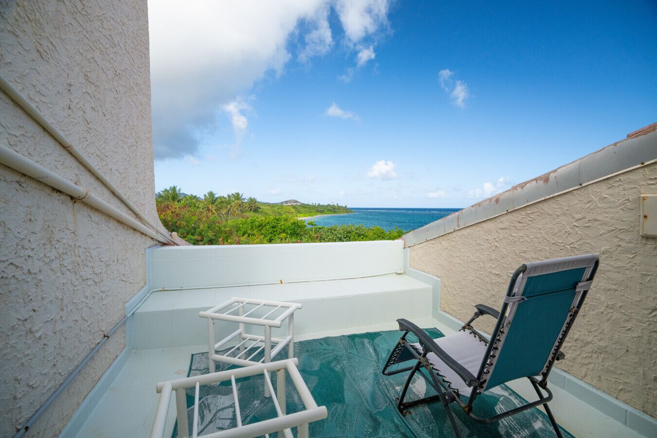 Un balcon avec vue sur l’océan, une chaise et une petite table.