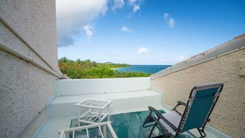 Un balcon avec vue sur l’océan, une chaise et une petite table.