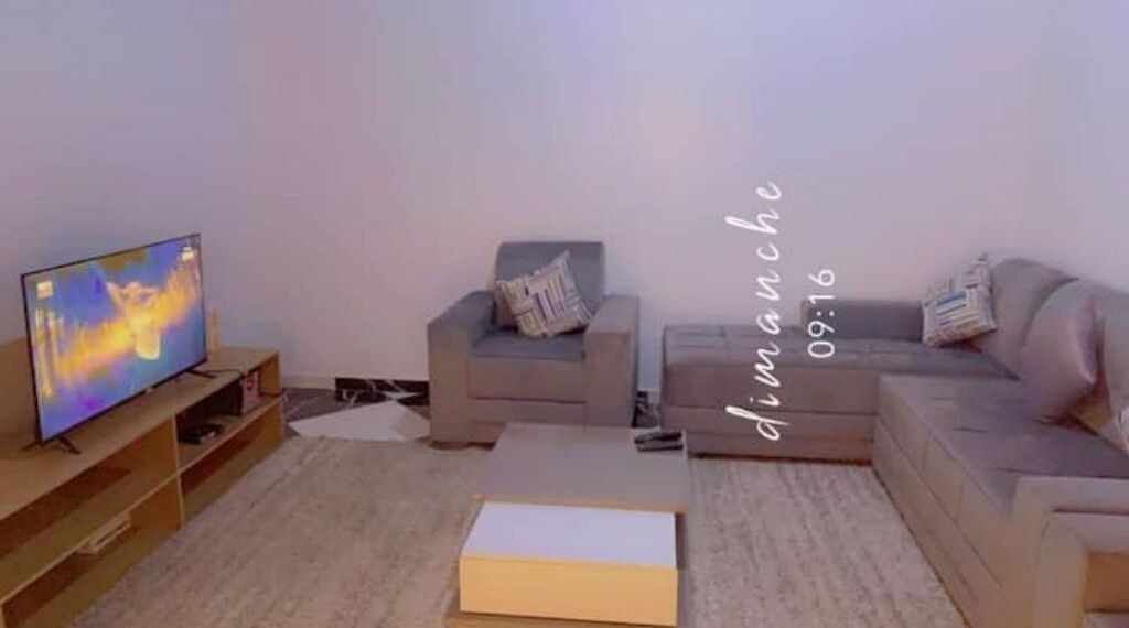 A living room with a television, two sofas, a coffee table, and a small table with a box.