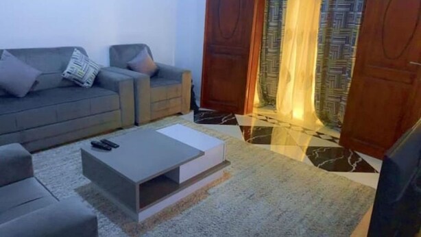 A living room with a grey sofa, a coffee table, and a patterned rug. - Furnished Studio, kotto, Douala. (Région du Littoral)