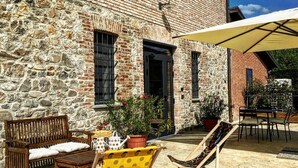 A stone building with a patio area featuring wooden furniture and a covered seating area. - Agriturismo I Tre Colli  (Solignano)