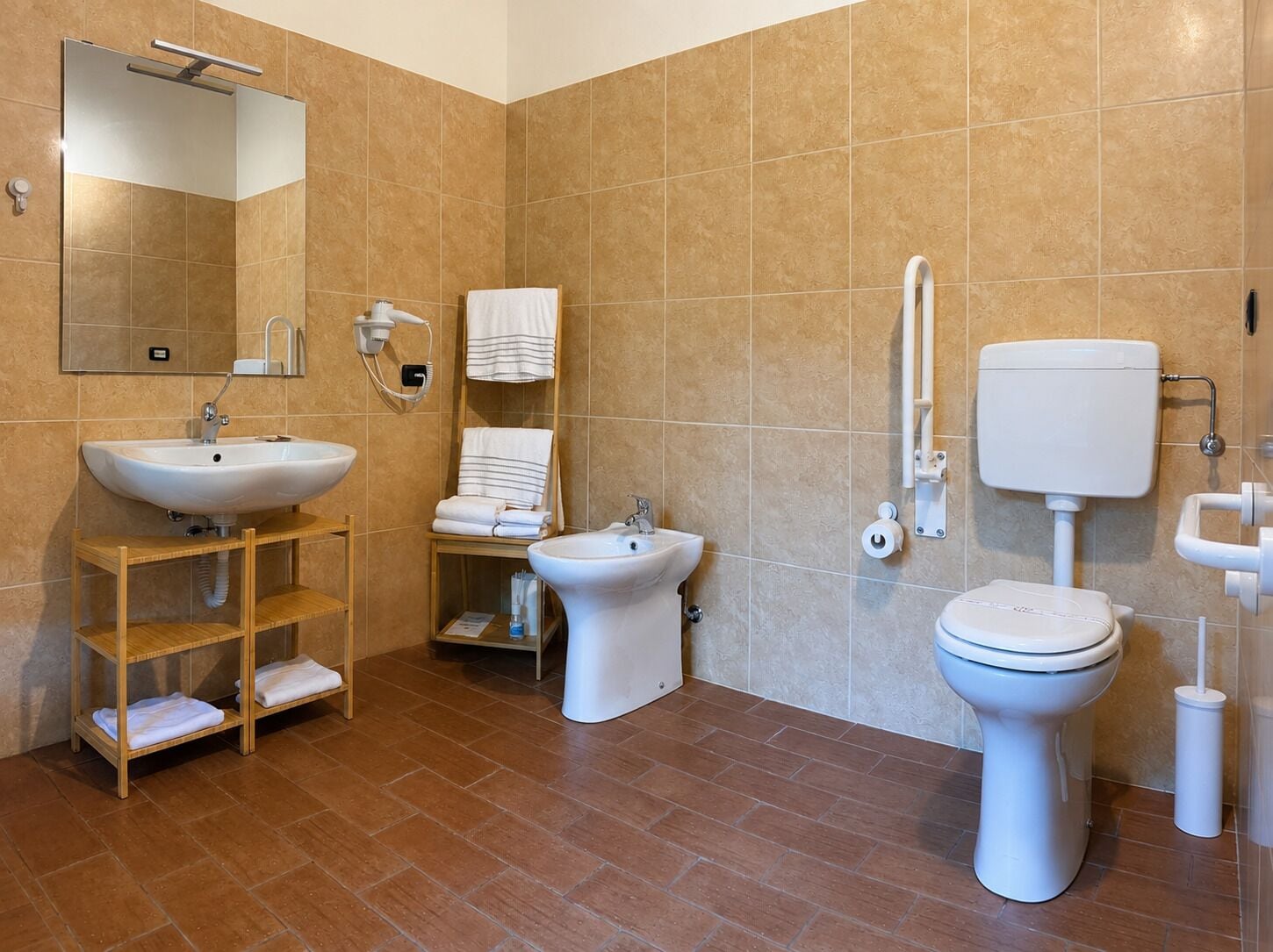 A modern bathroom with a sink, bidet, toilet, and a mirror.