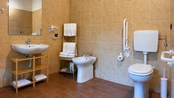 A modern bathroom with a sink, bidet, toilet, and a mirror.
