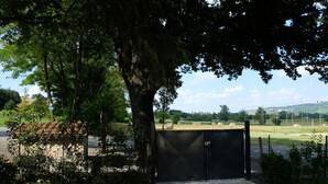 A gated area with a paved path leading to a field of hay bales. - Agriturismo I Tre Colli  (Solignano)